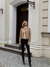 a lady wears a camel cropped jacket with black skinny jeans and black boots